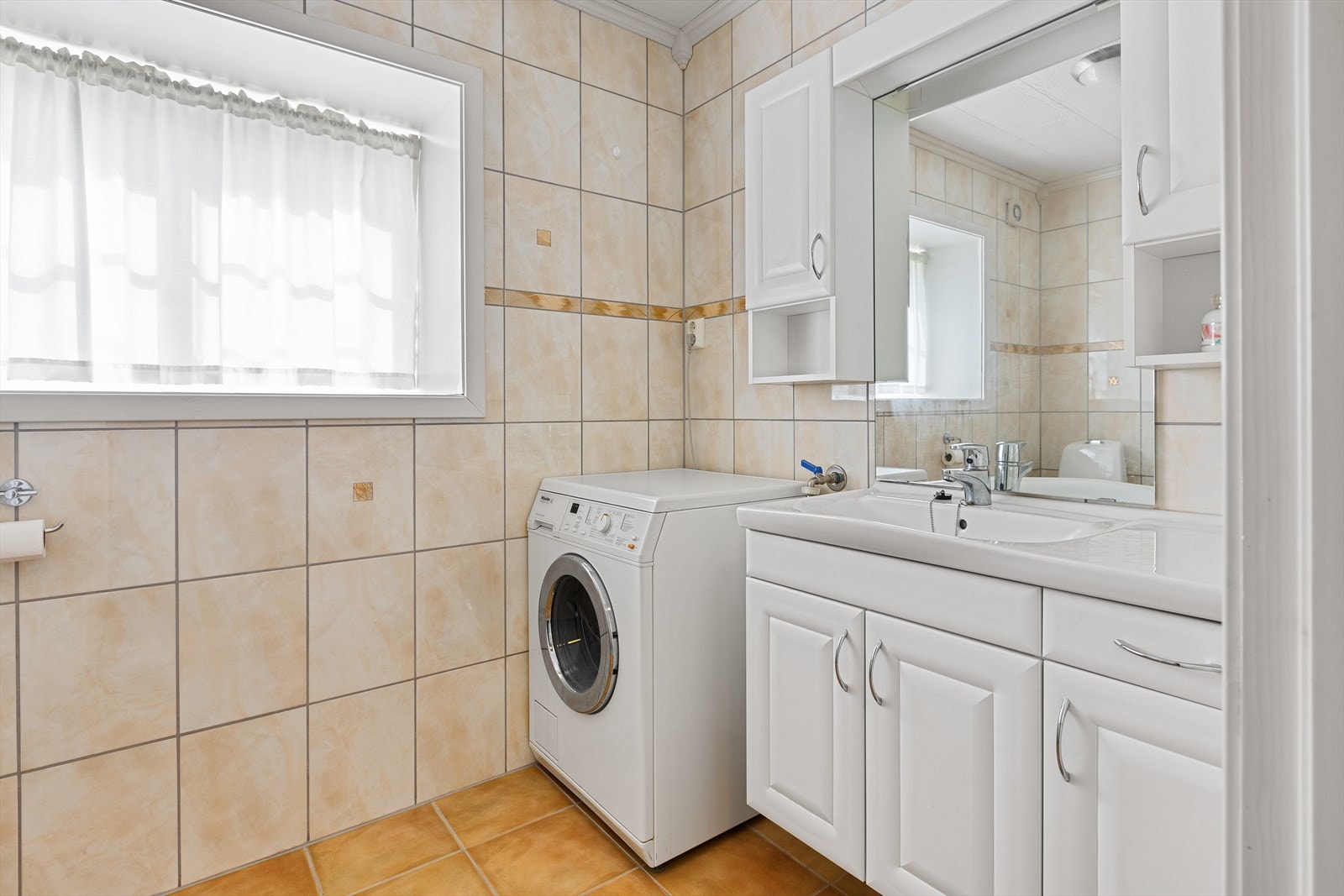 I etasjen er det et lyst bad fra 2005. Badet har flislagte vegger og flislagt gulv med varmekabler. Lys baderomsinnredning, dusj med glassdør/vegg, toalett og opplegg til vaskemaskin. Det er elektrisk styrt vifte i yttervegg. Galleribilde