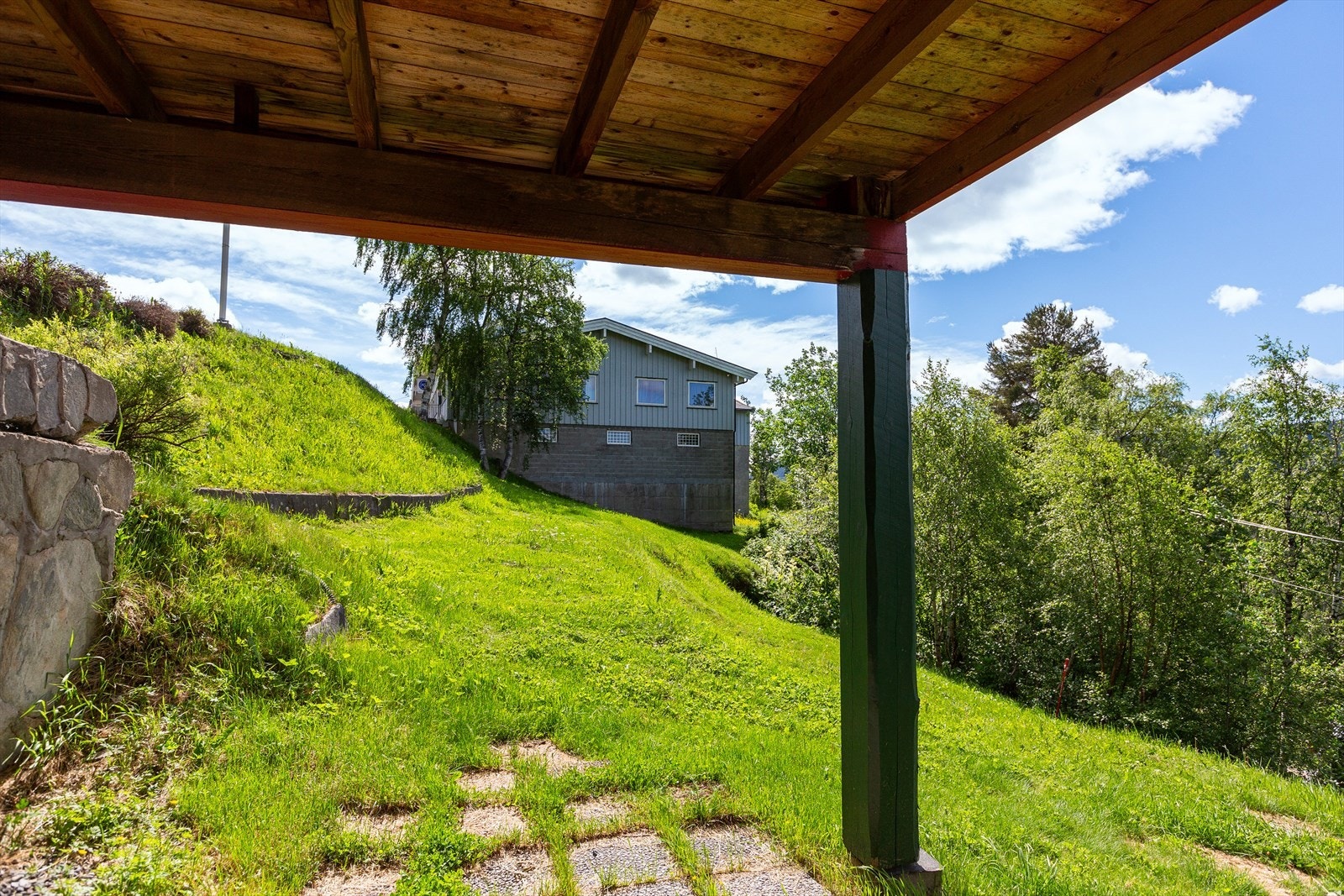 Fra boden i kjelleren er det utgang til overbygd uteplass, plen og beplantning. Galleribilde