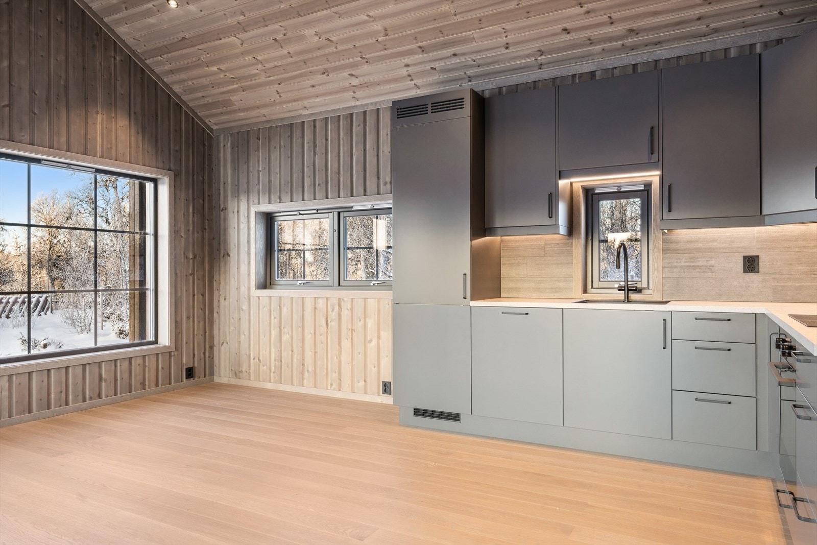 Med stue og kjøkken i åpen løsning blir hytta ekstra romslig og sosial. Her er det stilig kjøkkeninnredning fra Strai i hjørneløsning. Galleribilde