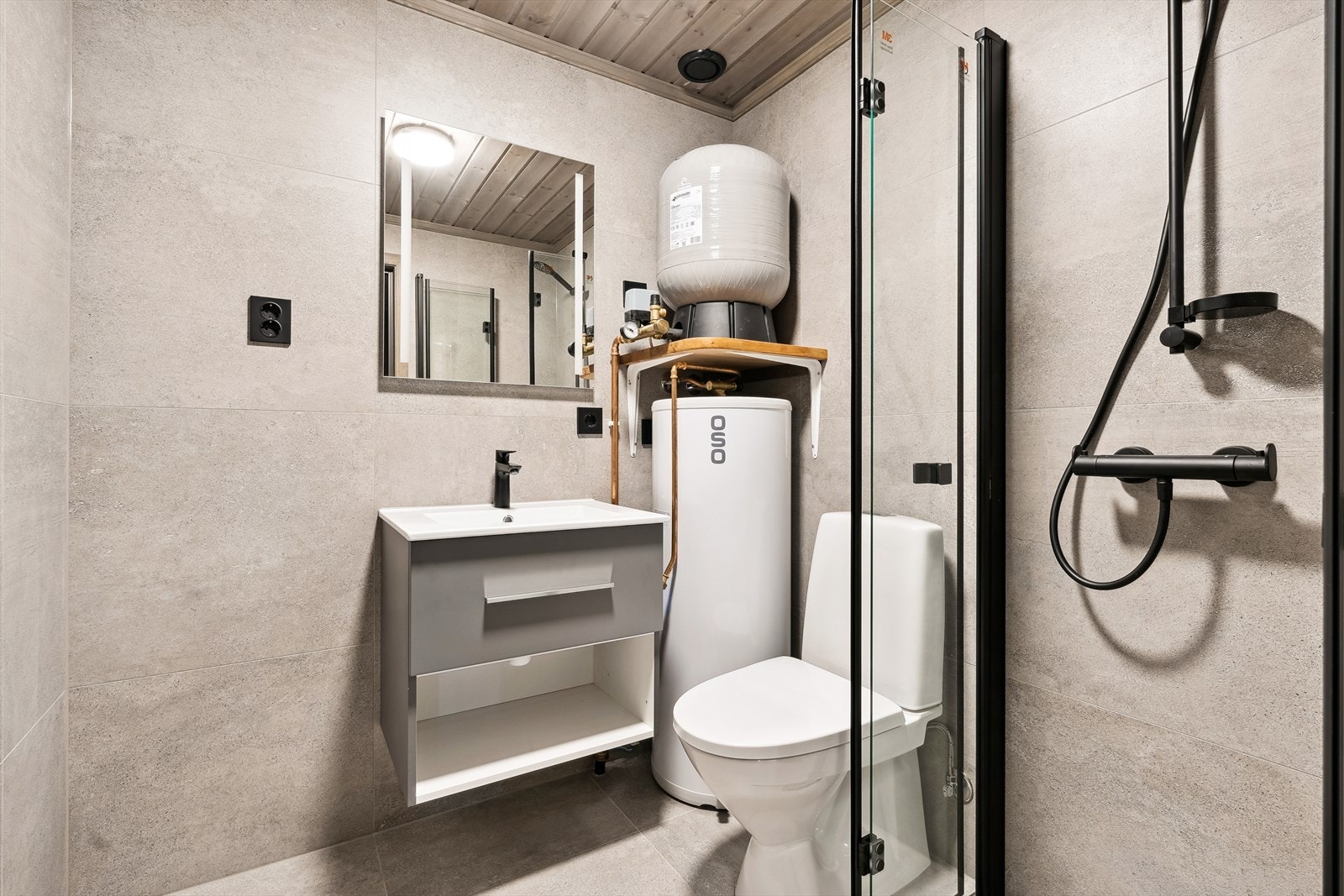 På hyttas andre bad er det servantskap, dusjnisje med glassdører, og gulvmontert toalett. Hyttas varmtvannstank er også plassert her. Galleribilde