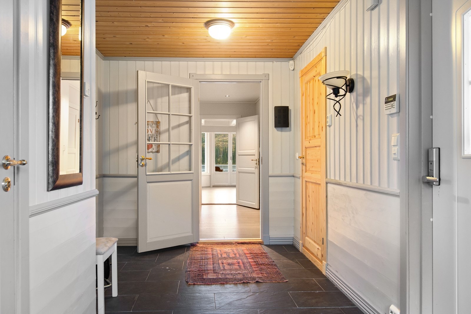 Fra et overbygget inngangsparti kommer du inn romslig gang med flislagt gulv. Her er det godt med plass til yttertøy og sko. Galleribilde