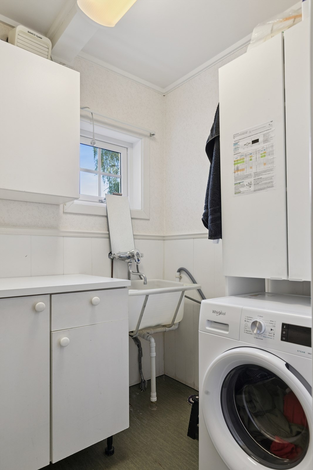 Et praktisk vaskerom med opplegg for vaskemaskin, utslagsvask og lagringsmuligheter. Galleribilde