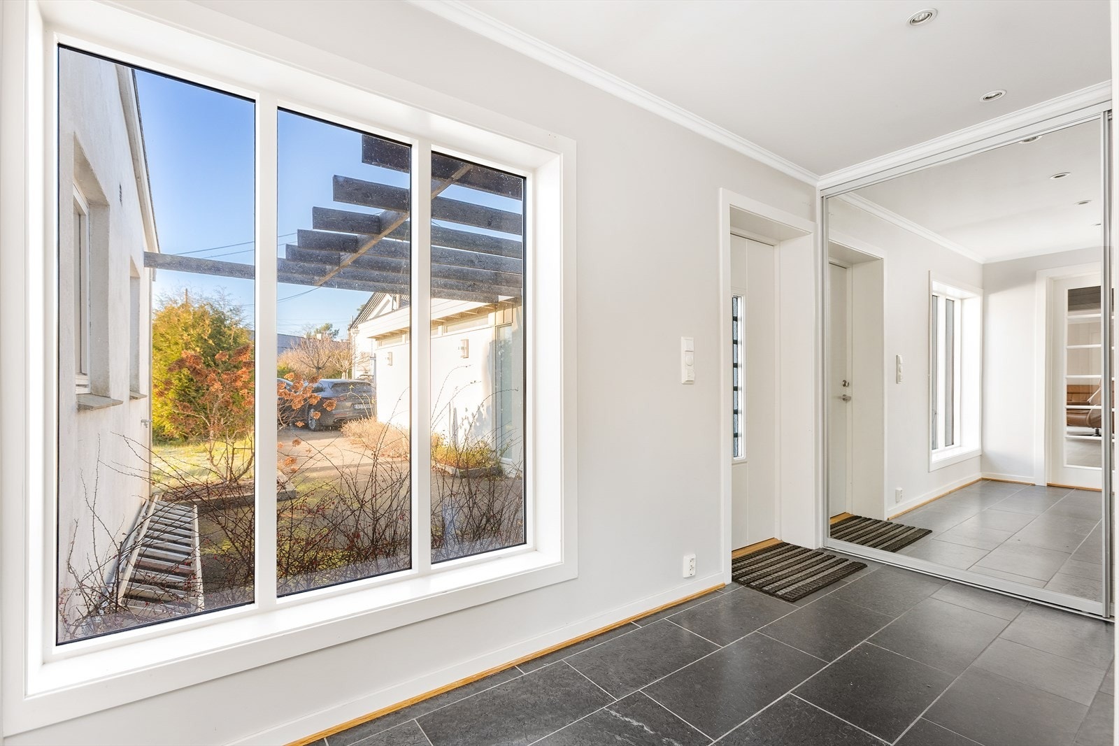 En romslig entré med speilgarderobe og flislagt gulv ønsker deg velkommen inn. Galleribilde