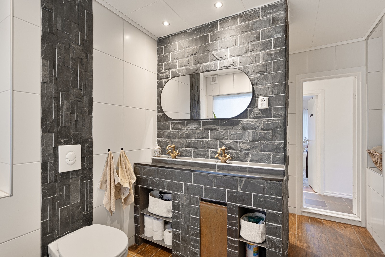 Romslig og stilrent flislagt bad, innredet med dobbelservant, vegghengt toalett og dusjnisje. Galleribilde