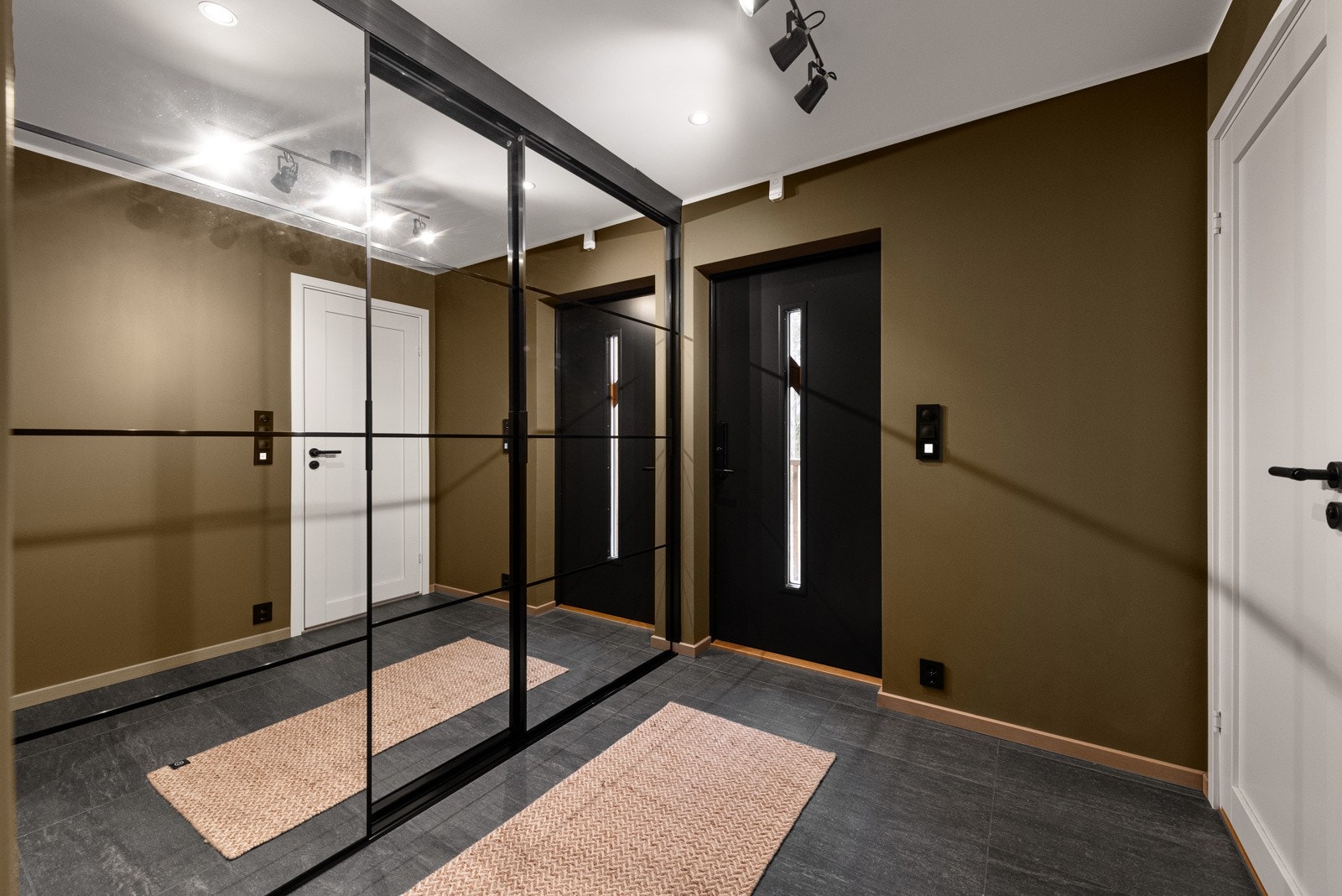 Boligens innbydende entré tilrettelegger godt for oppbevaring av uteklær med trippel skyvedørsgarderobe med speilfornt. Galleribilde