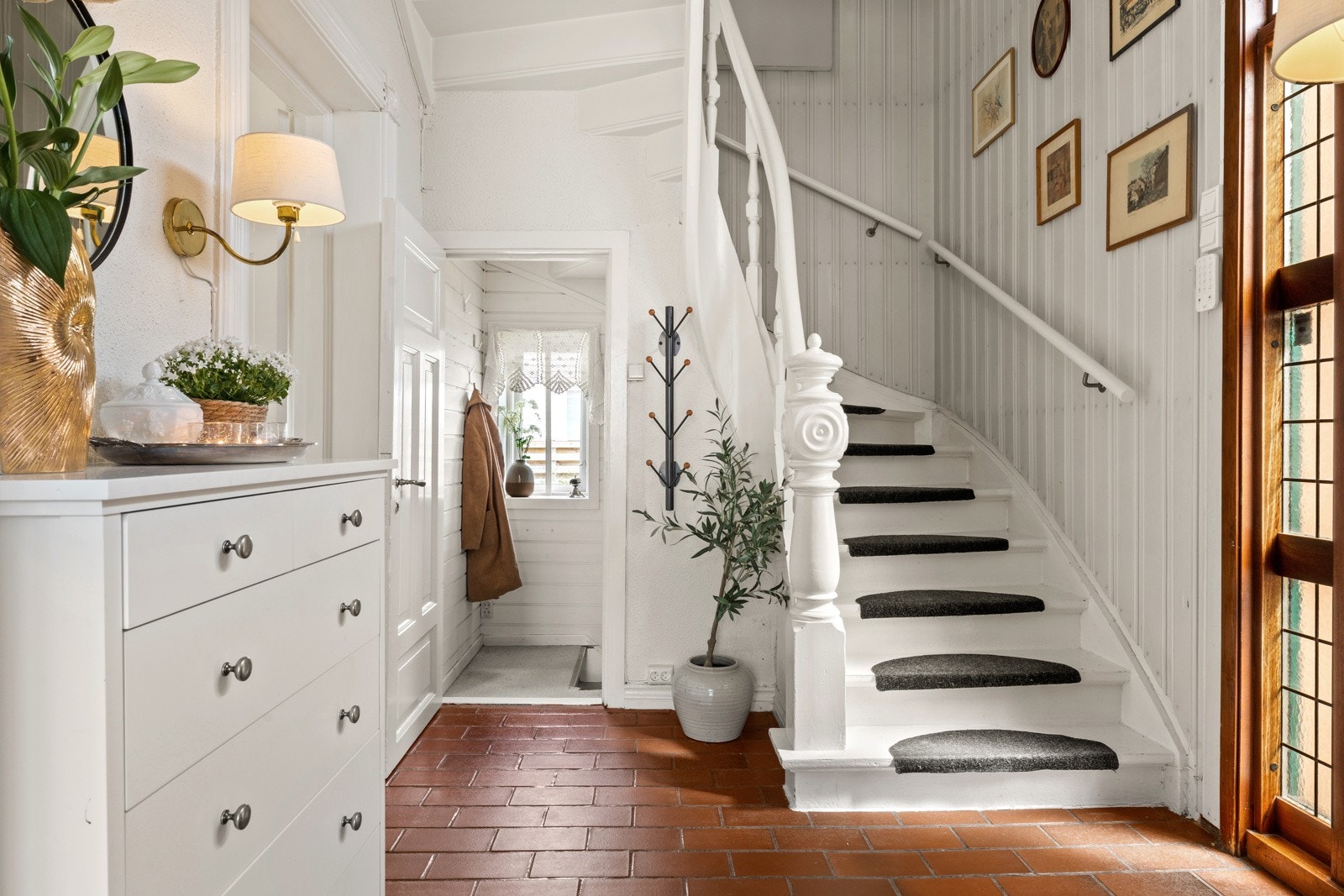 Allerede i inngangshallen ønskes du velkommen av en vakker trapp som leder opp til andre etasje. Dører fører inn til de vakre stuene & biblioteket. Også inngang til kjøkken. Nedgang til kjelelr. Fliser på gulv. Galleribilde