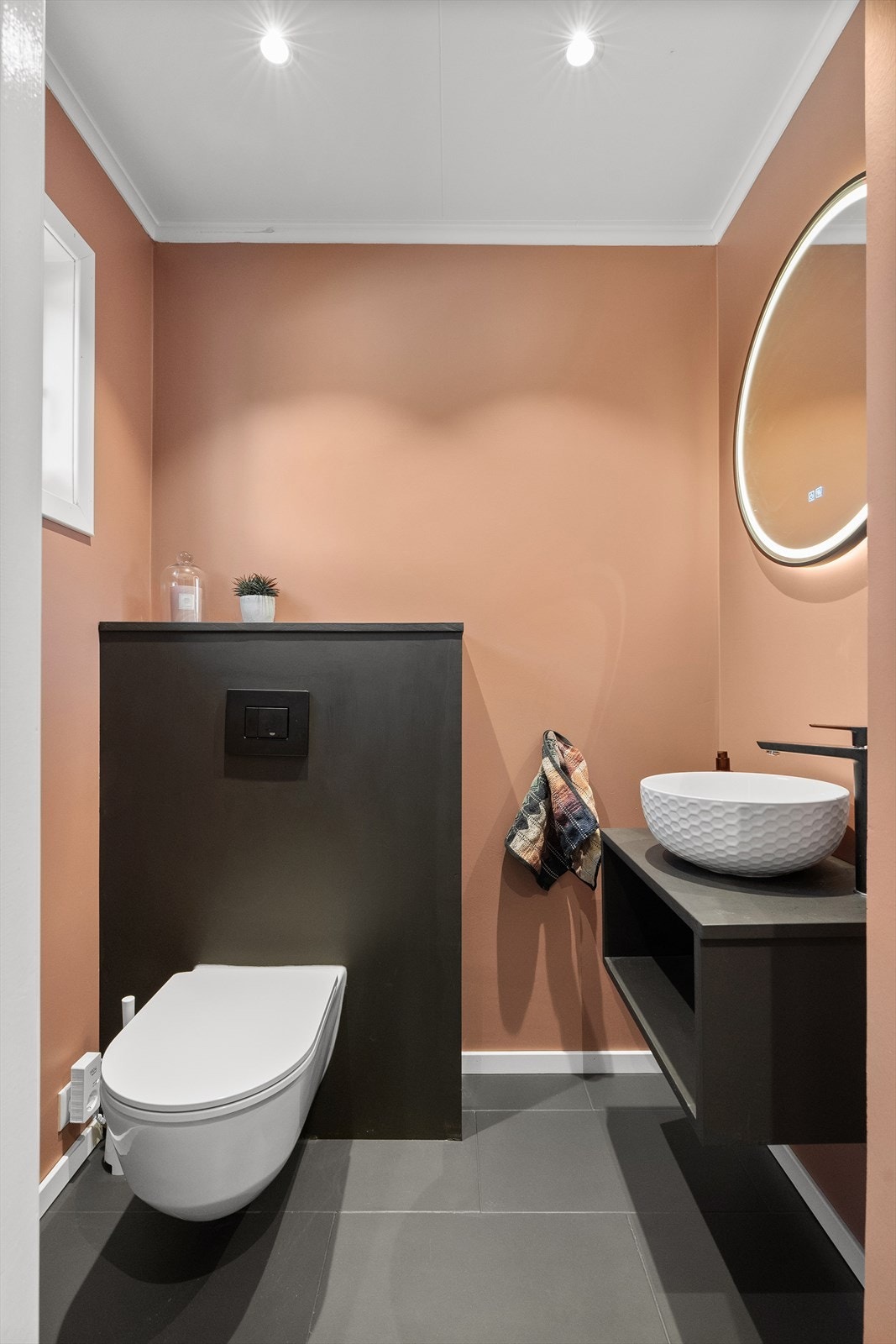 Praktisk toalettrom med elektrisk gulvvarme og downlights i himlingen, oppgradert i 2024. Rommet er innredet med vegghengt klosett og servant på innredning. Galleribilde