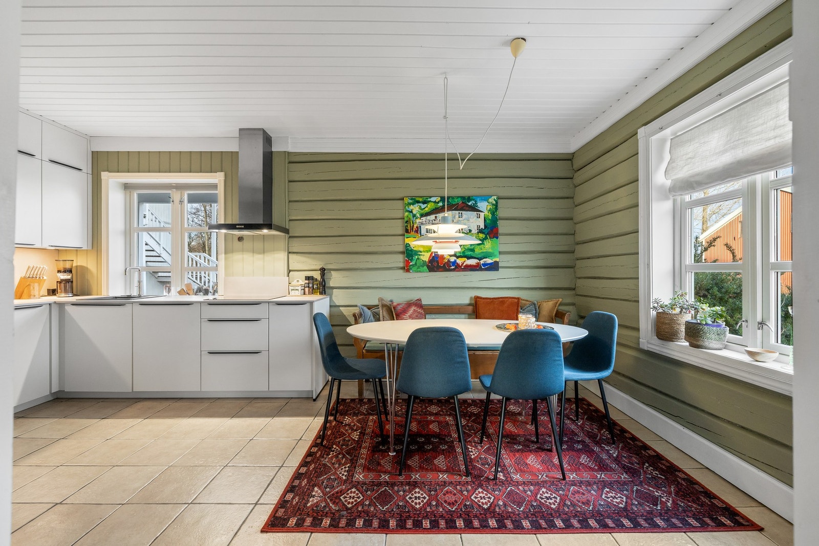 Beige fliser med varme er lagt på gulvet, kombinert med fine tømmervegger malt i en olivengrønn fargetone Galleribilde