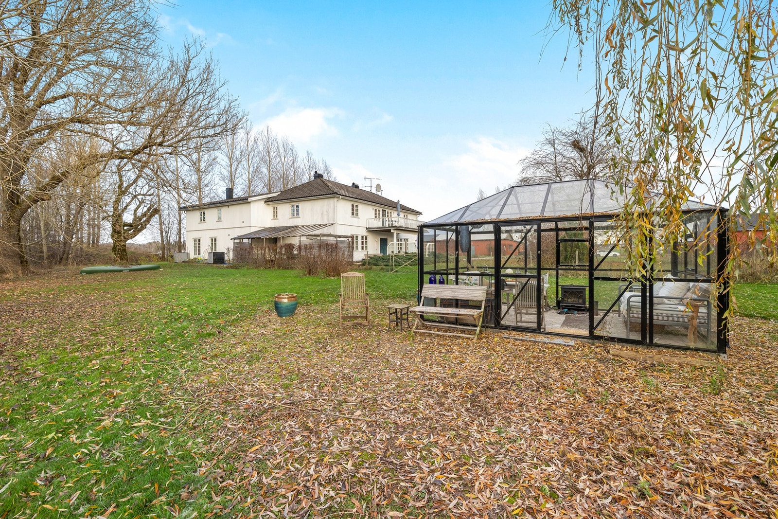 Gruslagte gangstier tar deg fra huset til gårdstunet, og et stort drivhus understreker idyllen på eiendommen Galleribilde