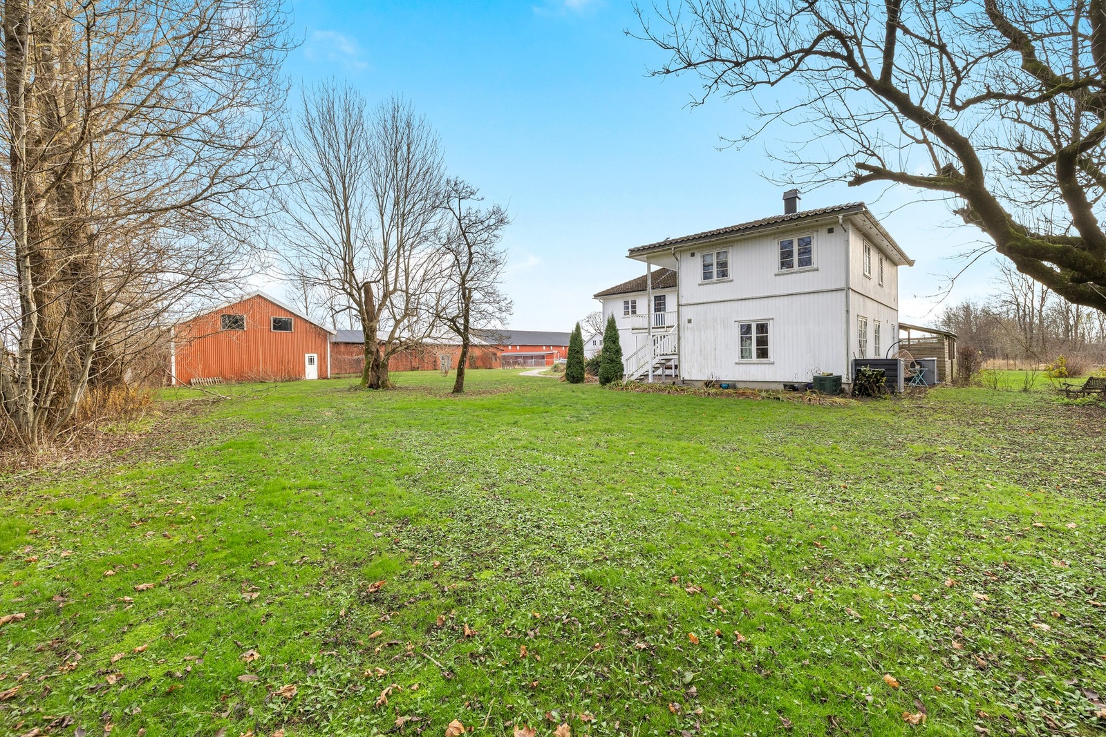 Rundt huset har tomten en flott hage med trær, busker, gjerder og stor gressplen for lek Galleribilde