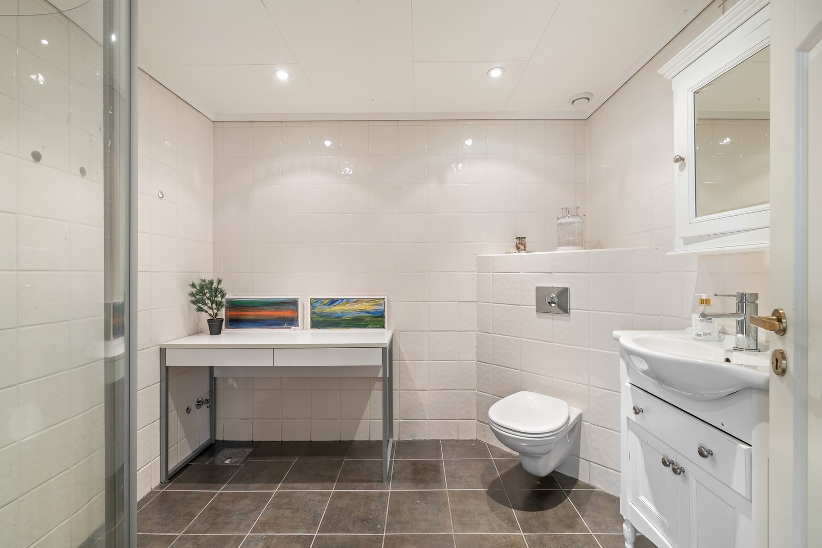 Varme er lagt i gulvet, og badet har downlights, vegghengt toalett og et dusjhjørne med innfellbare dører Galleribilde