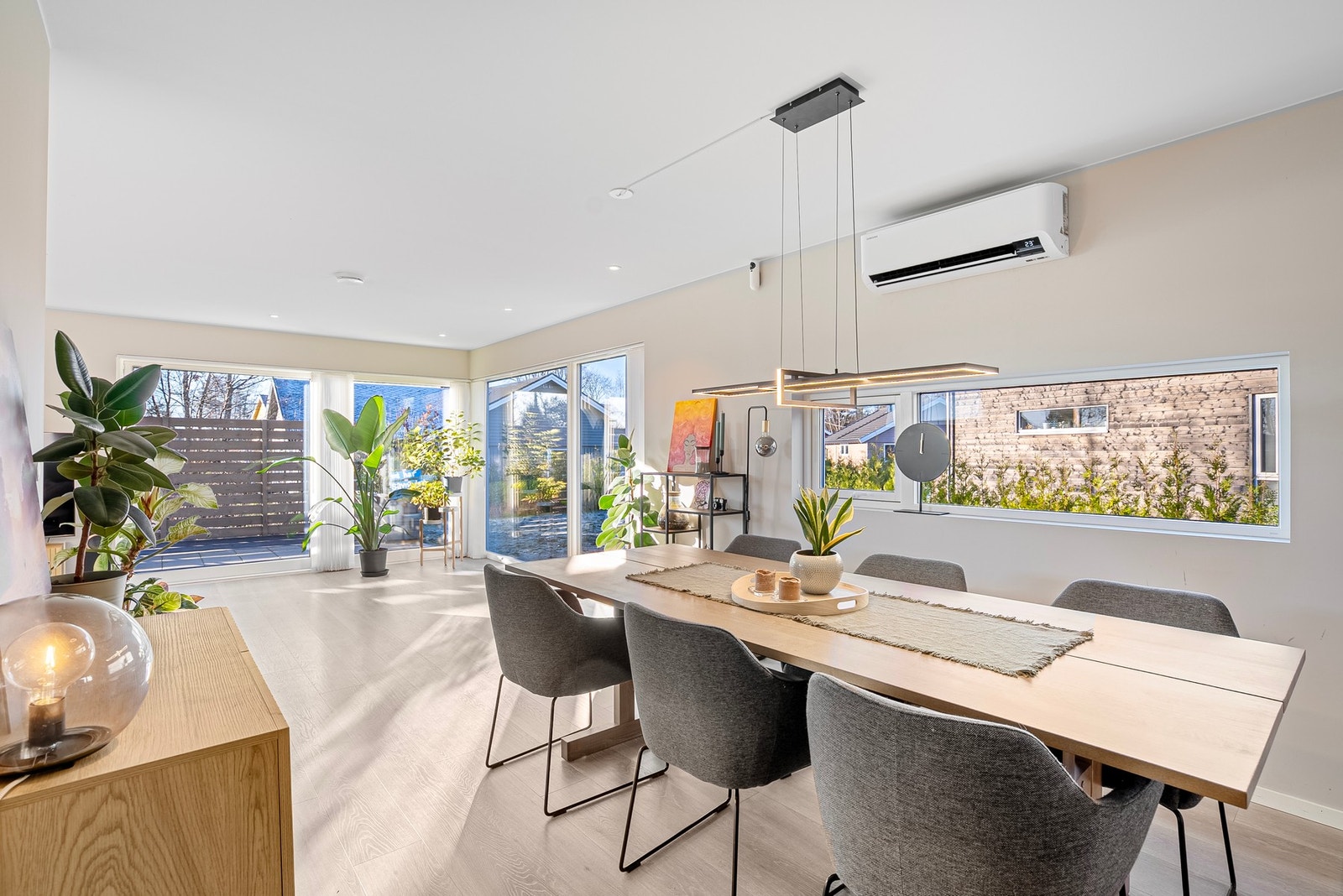 Godt lysinnslipp fra kjøkkenvinduer, spisestue og gulv-til-tak-vinduer mot uteplassen gir et lyst og åpent rom med herlig romfølelse Galleribilde