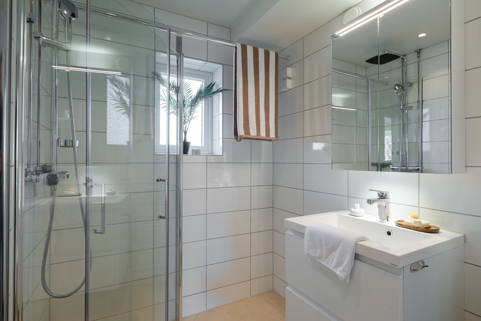 Her finner du et lunt og godt gulv med varmekabler, dusjhjørne med glassdører, vegghengt toalett, servant med innredning og opplegg for vaskemaskin. Galleribilde