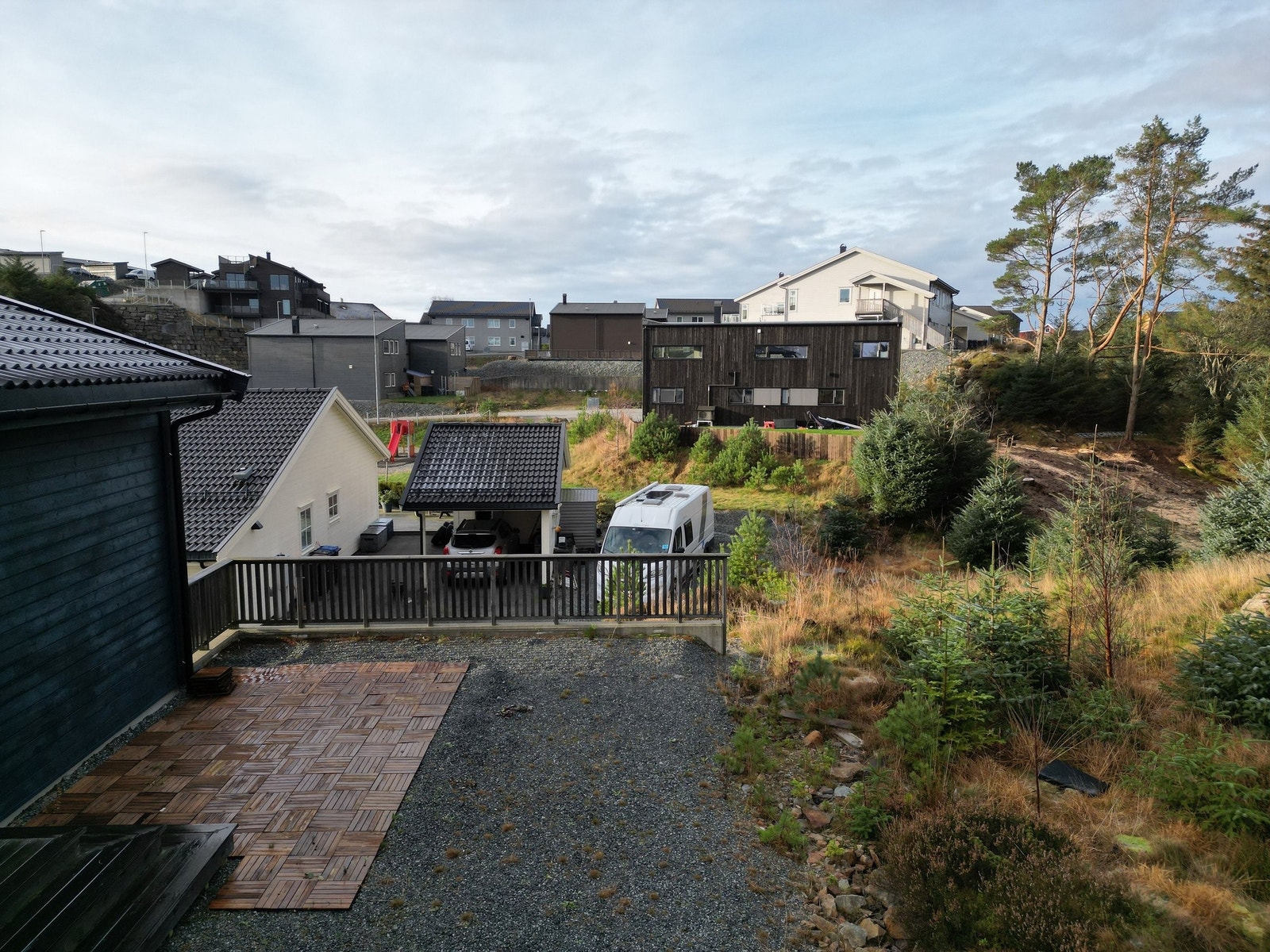 Utsikt frå eigedomen mot nabolaget og dei naturlege omgivnadene. Her kan ein nyte kveldssola frå uteplassen, med lune og grønne omgivnader som gir ein behageleg og fredfull atmosfære. Galleribilde