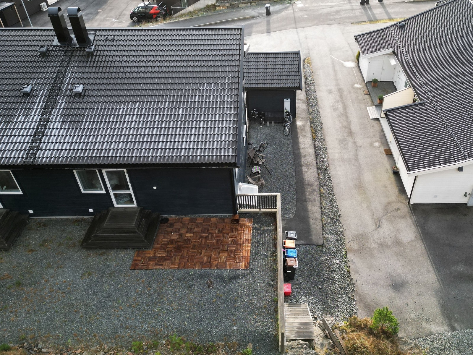 Oversiktsbilete av eigedomen med uteplass, praktisk innkøyrsel og tilkomst til inngangspartiet. Her får du ein skjermet og vedlikehaldsvenleg uteplass med gode parkeringsmoglegheiter og korte avstandar til nabolaget rundt. Galleribilde