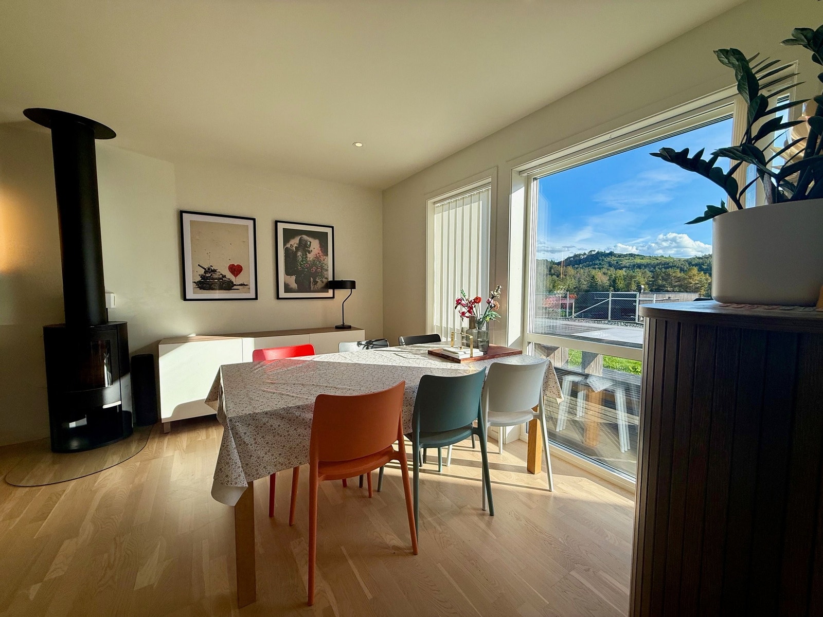 Elegant stue i sømløs overgang til kjøkkenet – med peis som luner og store vindusflater som slipper inn rikelig dagslys. Galleribilde