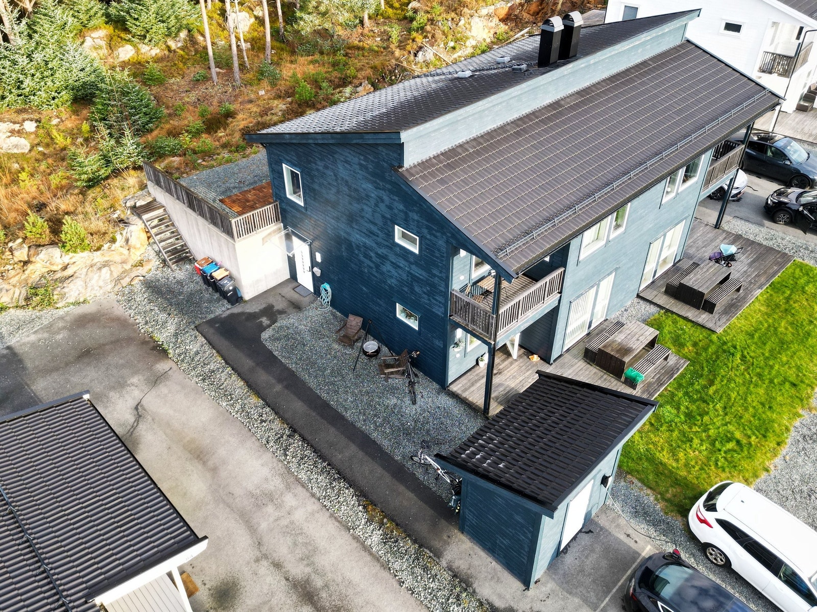 Luftfoto som viser bustaden sin bakside med triveleg uteplass, eigen sportsbod og skjermet adkomstområde. Tomta har LNF område i bakkant. Galleribilde