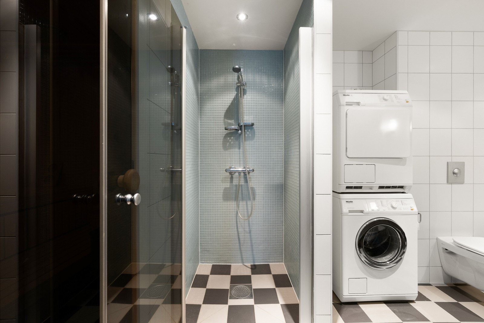 Bad 1 er innredet med en dobbel servant med underskap, speil med belysning, dusjnisje, badekar og et vegghengt toalett. Det er også opplegg for vaskemaskin og tilgang til badstue. Galleribilde