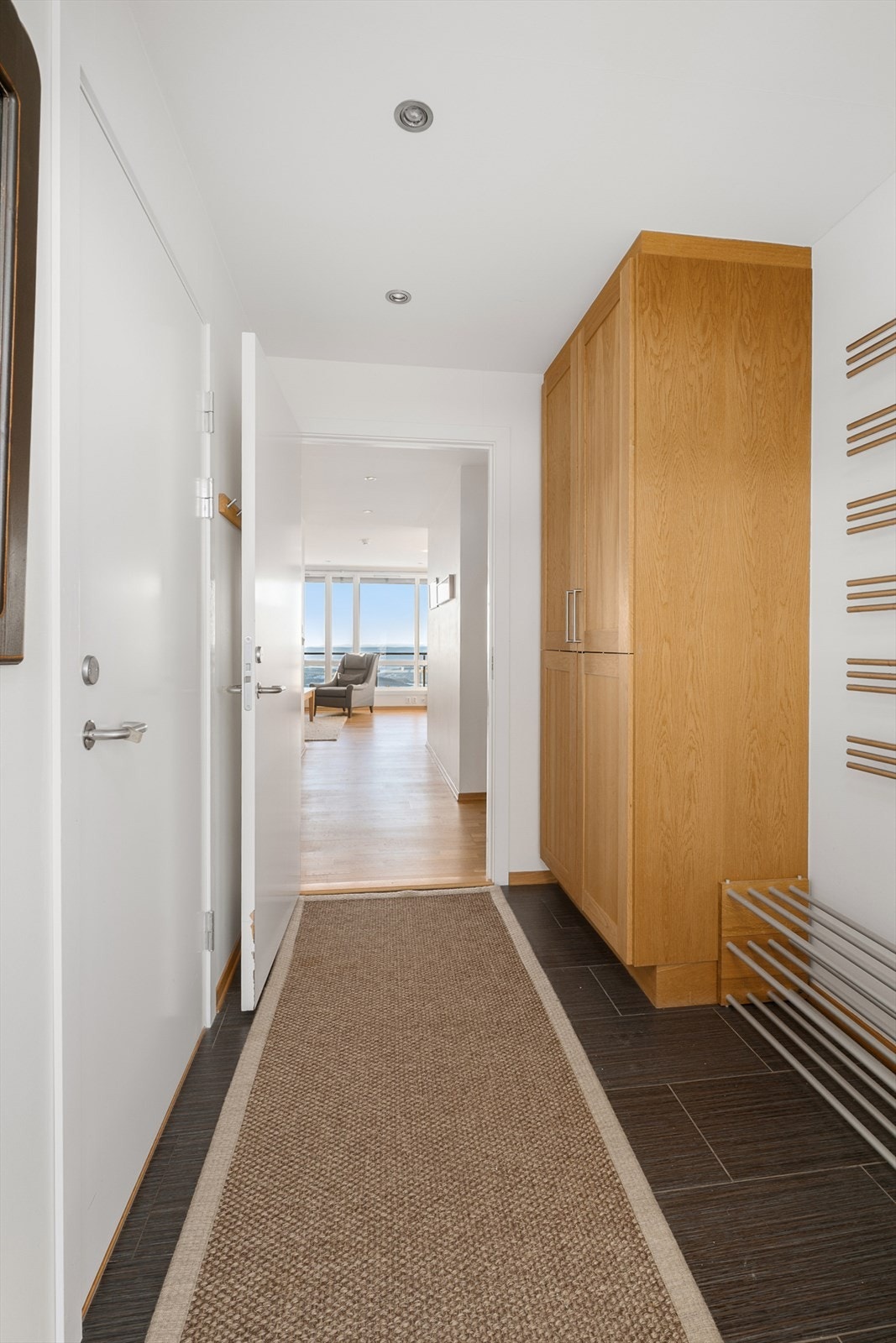 Entréen er romslig og pen, innredet med mørke gulvfliser med gulvvarme, downlights og lyse veggflater. Galleribilde