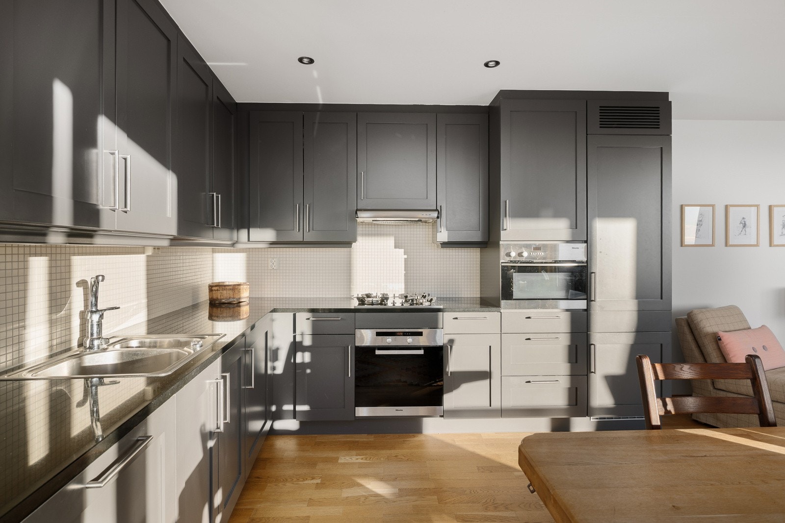 Benkeplaten i stein med nedfelt kjøkkenkum gir god funksjonalitet og flott uttrykk, flislagt vegg med belysning over arbeidsflaten skaper både funksjonalitet og stil. Galleribilde