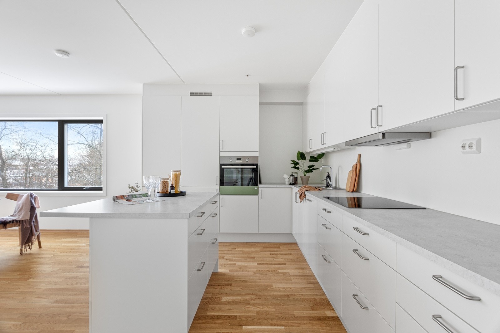 Lekkert kjøkken i åpen løsning med stuen. Kjøkkenet leveres i hvit utførsel med laminert lysegrå benkeplate, takhøy kjøkkeninnredning og integrerte hvitevarer. Galleribilde