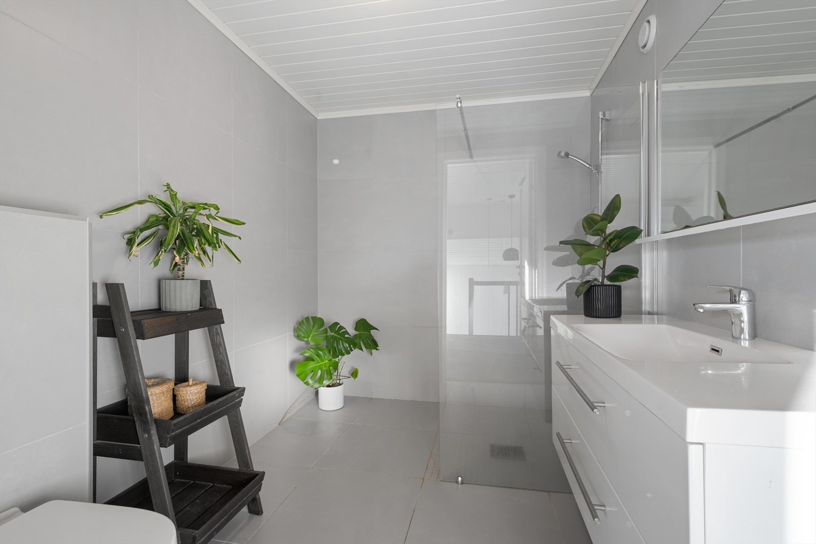 Badet har fliser på gulv og vegger, dushjøre og vegghengt WC Galleribilde