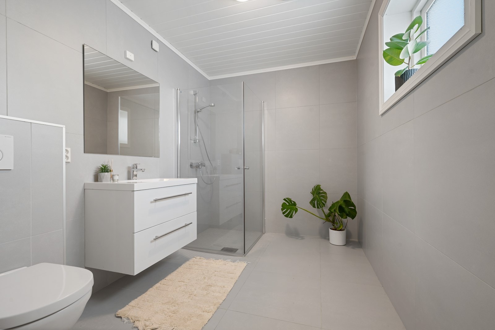 Bad med fliser på gulv og vegger, badet har dushjørne og vegghengt WC. Galleribilde