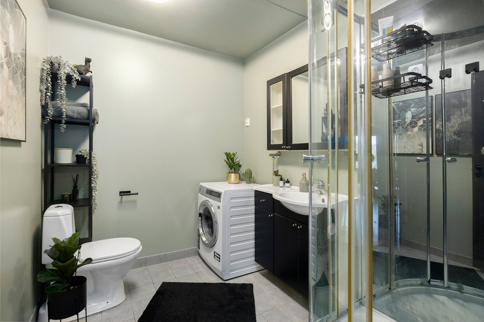Badet har flislagt gulv og er innredet med dusjkabinett, toalett, nedfelt servant m/innredning og opplegg for vaskemaskin. Galleribilde
