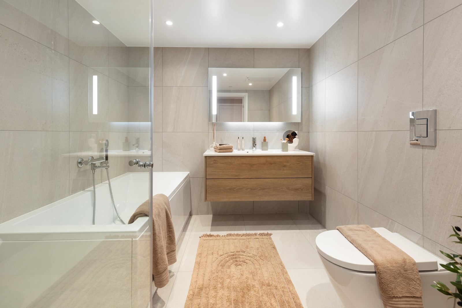 Badet er utstyrt med badekar, dusjhjørne, vegghengt toalett og en lekker baderomsinnredning. Galleribilde