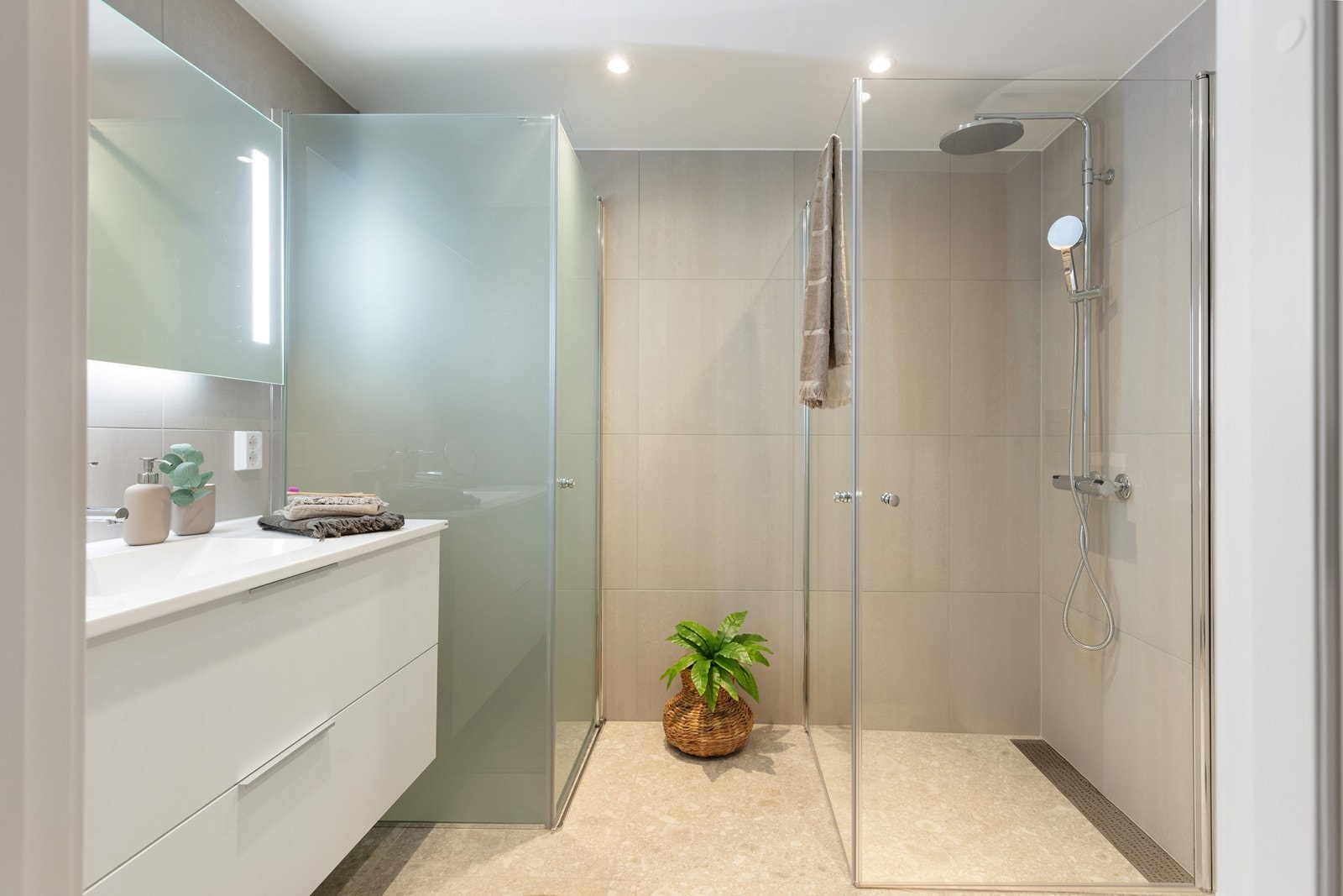 Leilighetens andre bad er også helfliset og har dusjhjørne med glassdører. Galleribilde