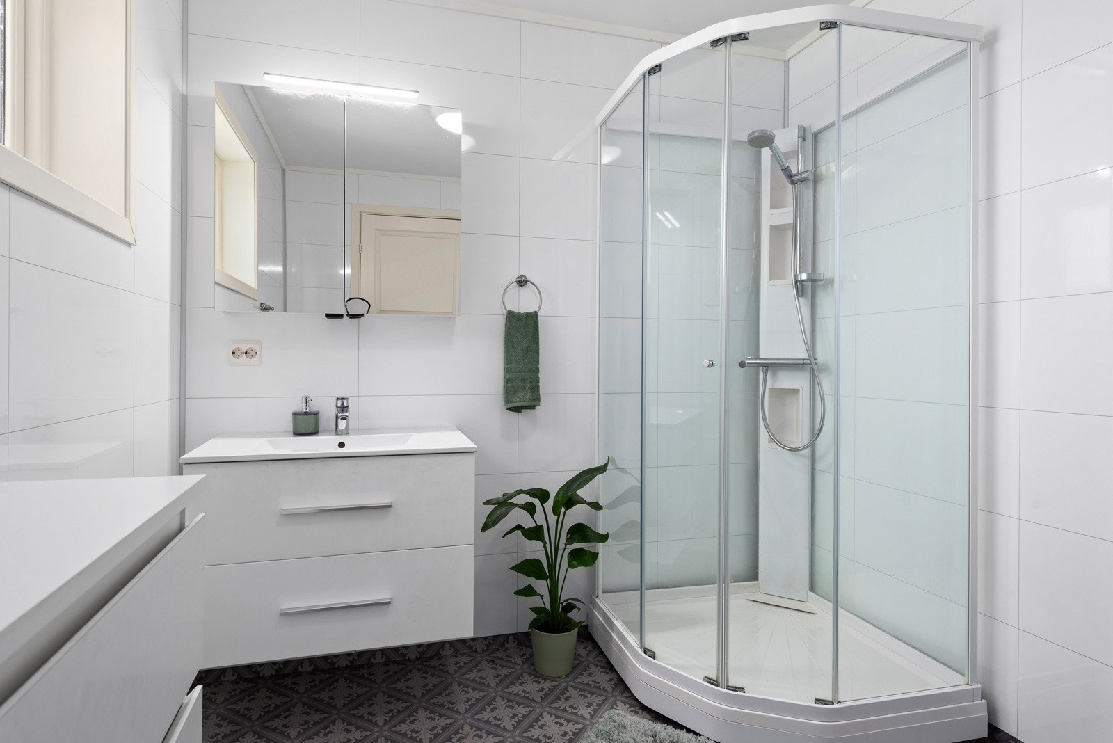 Tidløst baderom med dusjkabinett og innredning med skuffeløsning. Speilskap for oppbevaring med overliggende lys. Galleribilde