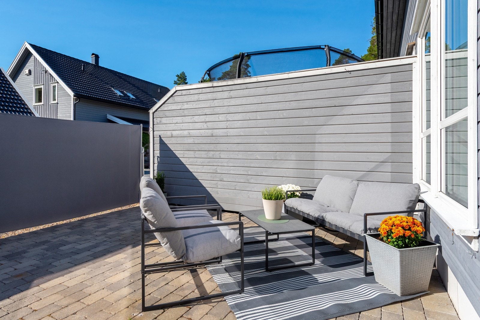 Solrik uteplass med flere møbleringsmuligheter og plass til både spisebord og sittegruppe. Galleribilde