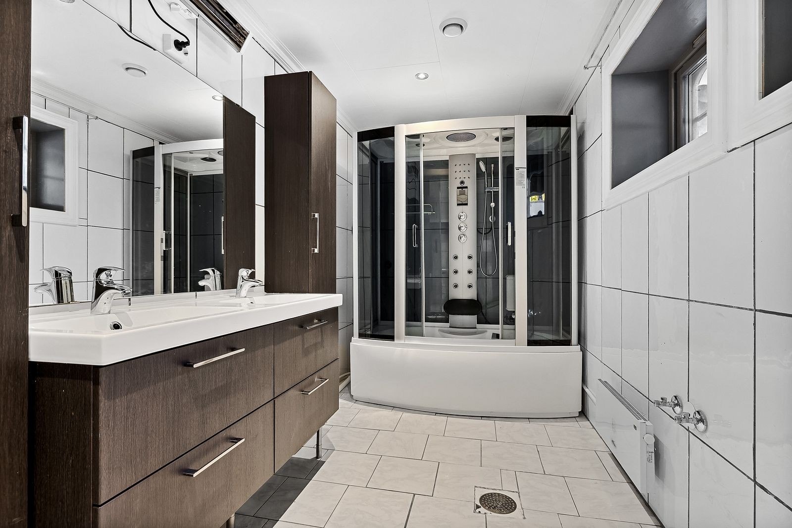 Stort bad innredet med dusjkabinett, servant, toalett, bide og opplegg til vaskemaskin. Galleribilde