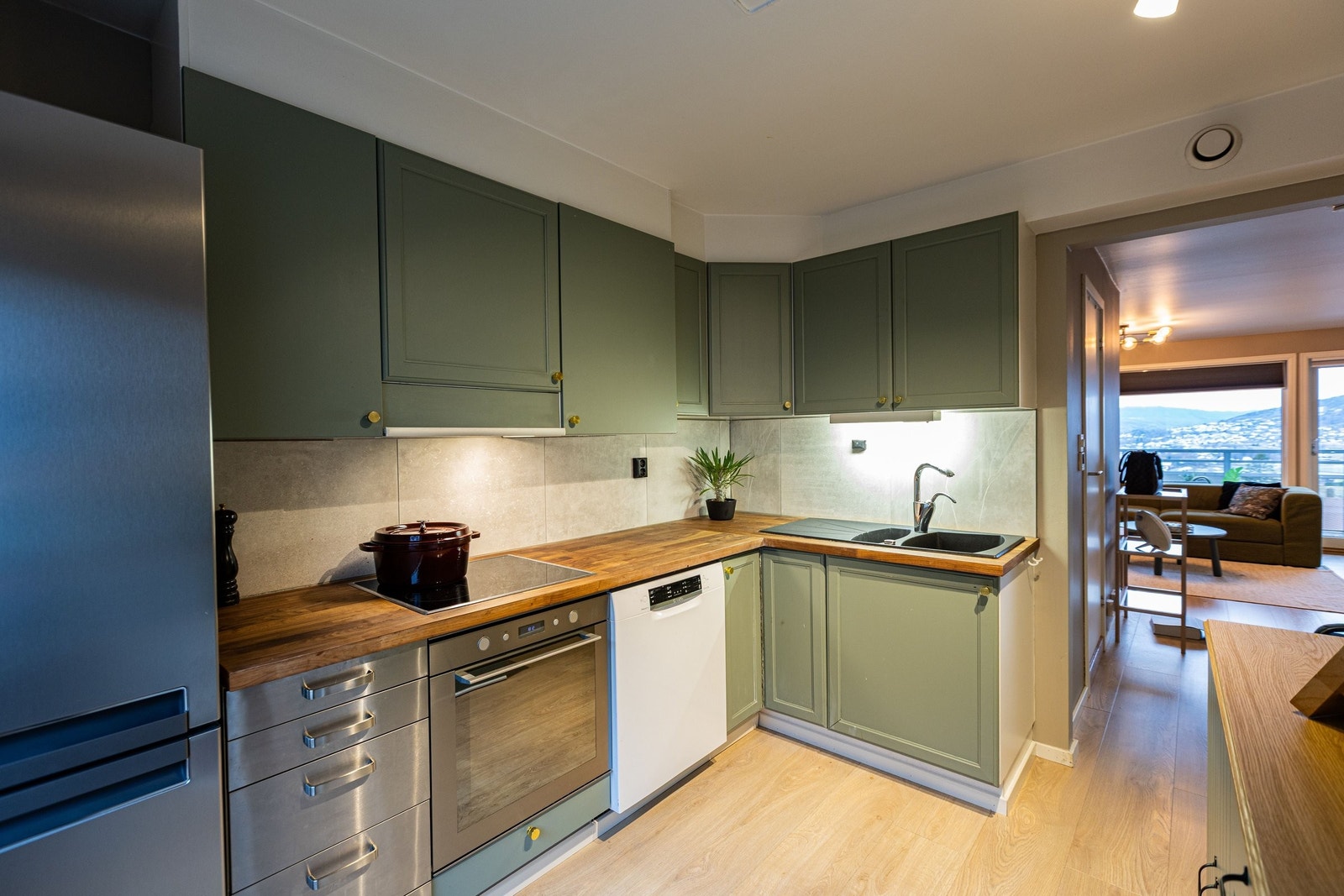 Stilrent kjøkken med nymalte fronter i dempet grønnfarge og benkeplate i heltre Galleribilde