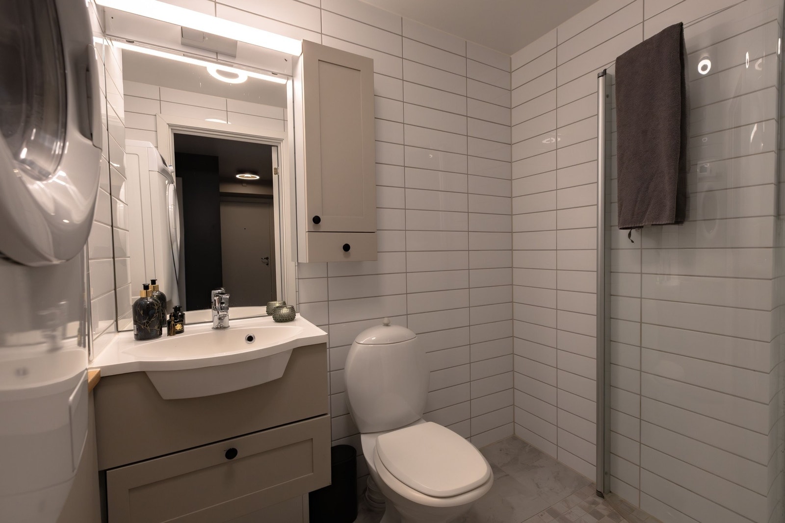 Flislagt bad med dusjhjørne, servant med oppbevaring og opplegg for vaskemaskin Galleribilde