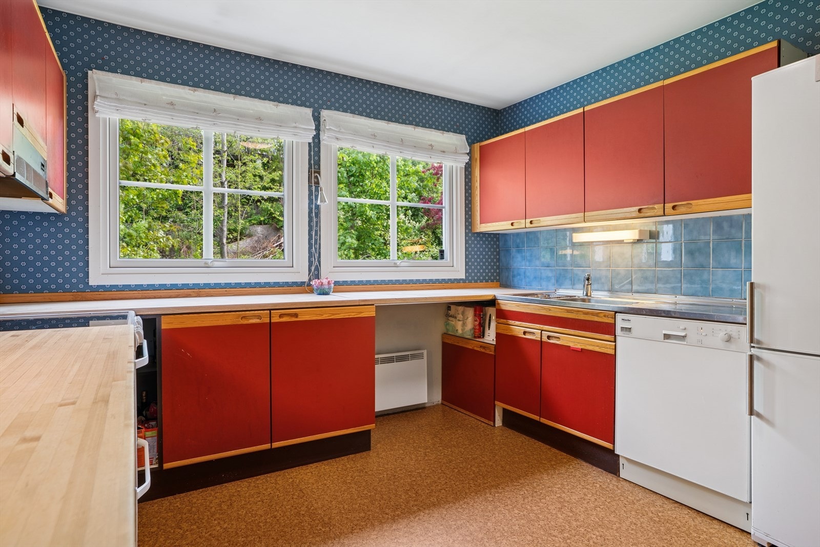 Benkebeslag i rustfritt stål med nedfelt oppvaskkum. Flisfelt mellom overskap og kjøkkenbenk. Galleribilde