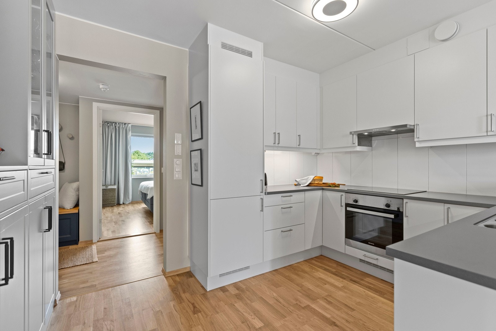 - Pent kjøkken med glatte fronter, laminert benkeplate, integrert kjøkkenkum og flislagt vegg over kjøkkenbenk - Galleribilde