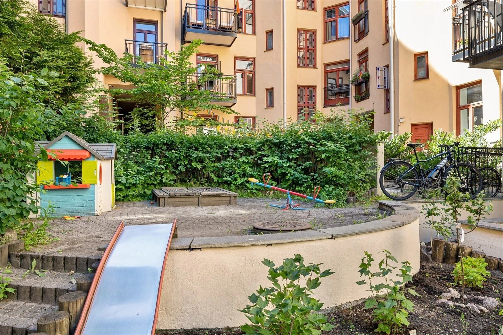 Bakgården består av bl.a. brostein, gressplen, sittegrupper, flott beplatning og trær Galleribilde