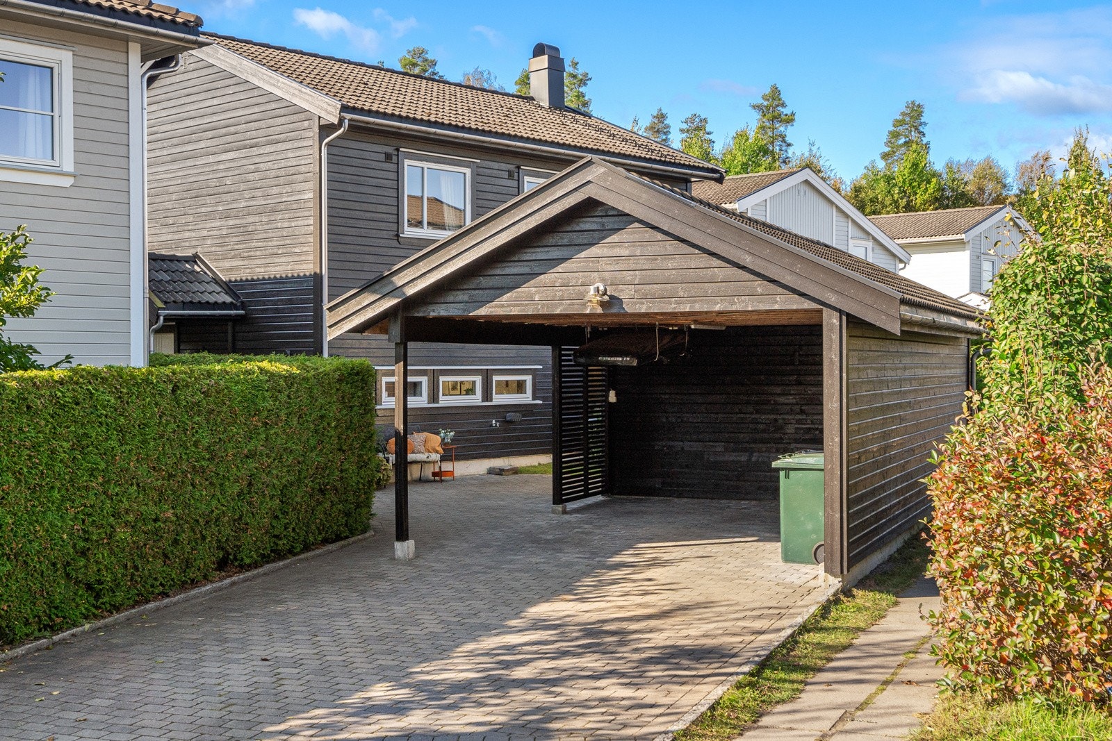 Innkjørsel til boligen med carport og bod. Innkjørselen er belagt med fin belegningssten Galleribilde