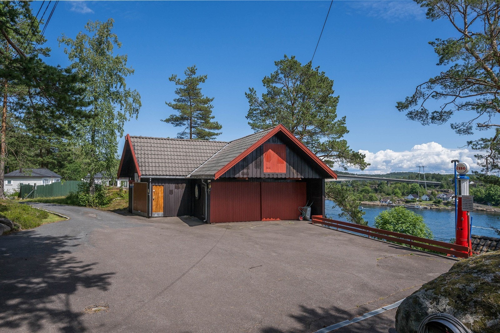 Skrånede tomt opparbeidet med asfaltert innkjøring og gårdsplass, heller/brostein på mark, forstøttningsmurer, trapper, blottlagt fjell, overbygget oljetank, lekestue, utestue med overbygg og utepeis, brygge, plenarealer og diverse beplantning. Galleribilde