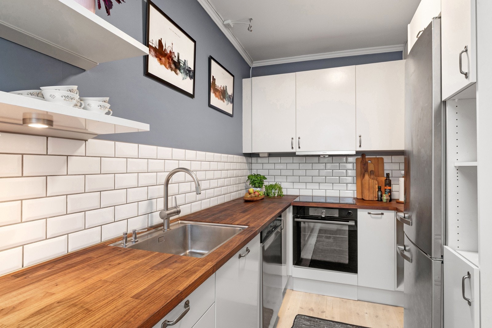 Kjøkkeninnredningen har glatte fronter, fliser mellom kjøkkenbenk og overskap, benkeplate av tre med nedfelt oppvaskkum. Galleribilde