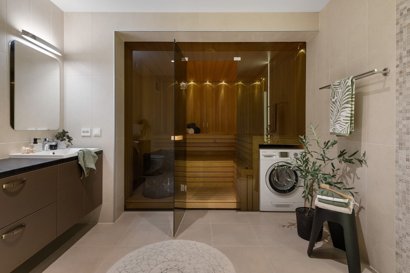 Luksuriøst baderom med fliser fra gulv til tak og stor badstue for maksimal velvære. Galleribilde