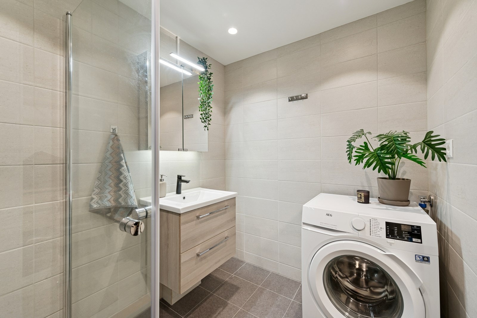 Moderne baderomsinnredning samt opplegg for vaskemaskin. Det er varmekabler i gulv. Galleribilde