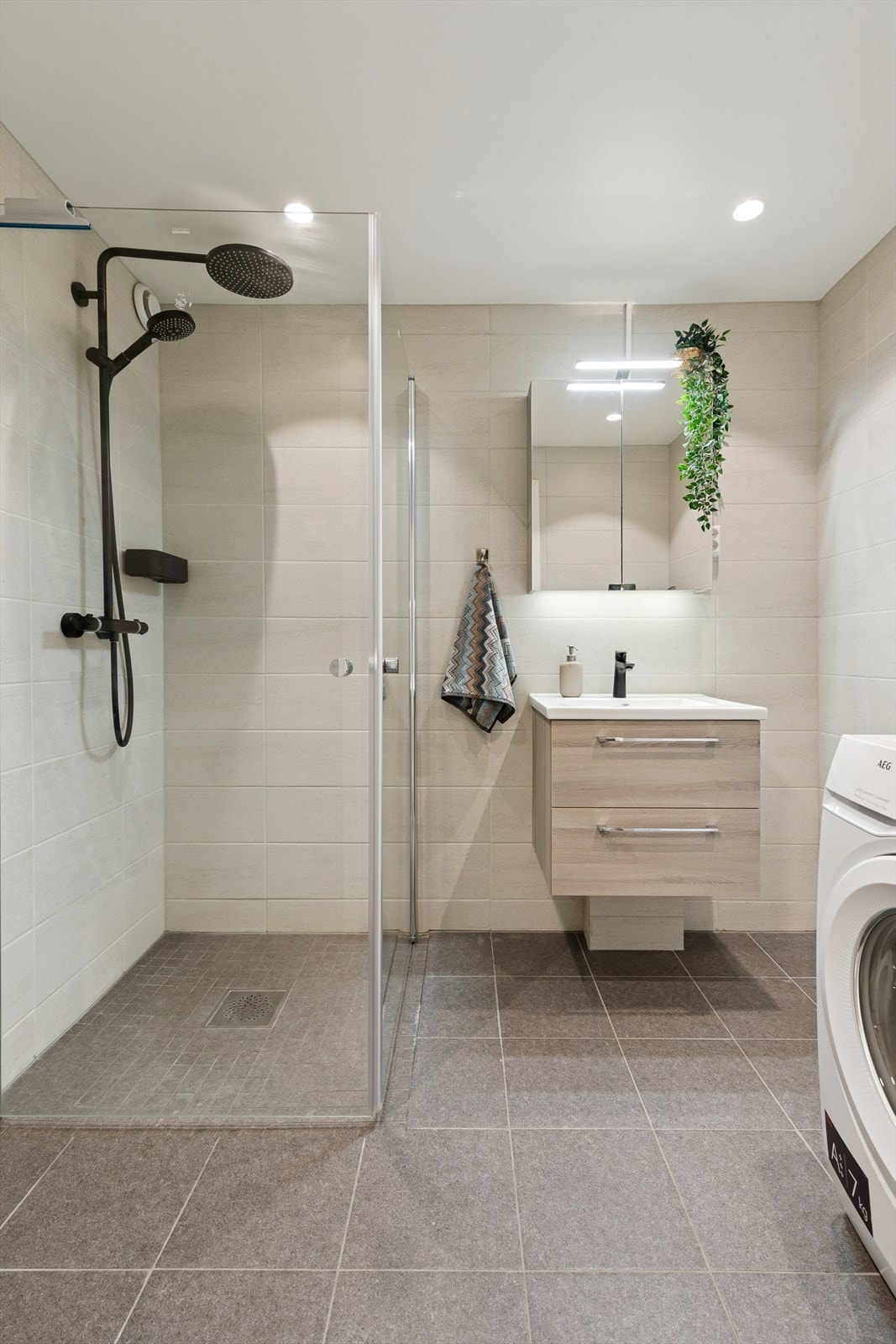 Delikat og lekkert flislagt bad fra 2021. Dusjhjørne med herlig regndusjarmatur samt hånddusj. Galleribilde