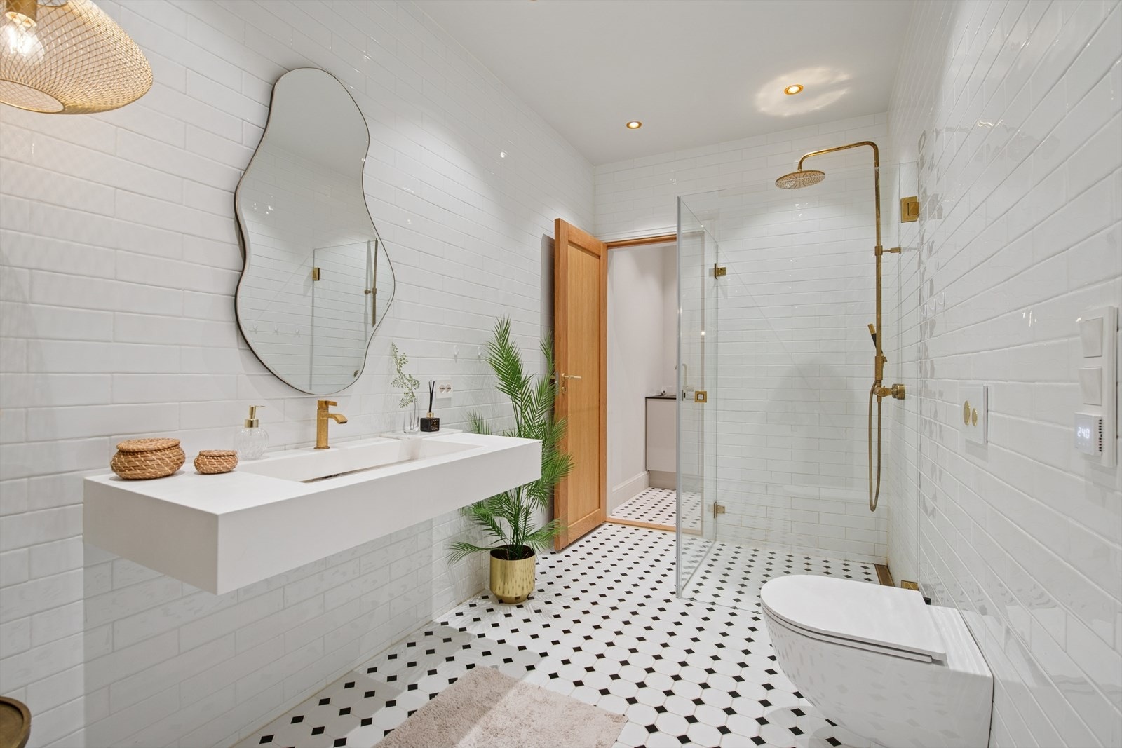 Dusjområdet har innfellbare dører og et veggmontert dusjsett i gull, med både hånd- og regndusj. Gulldetaljene går igjen i veggfestene på glassdørene. Galleribilde