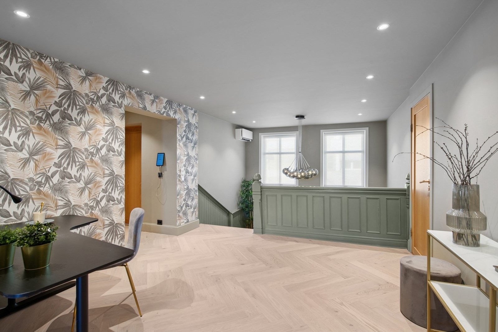 Den pene trappen opp leder til leilighetens hovedetasje, hvor du blir møtt av et imponerende rom med vakker fiskebeinsparkett på gulvet og dekorativ tapet på deler av veggene. Galleribilde