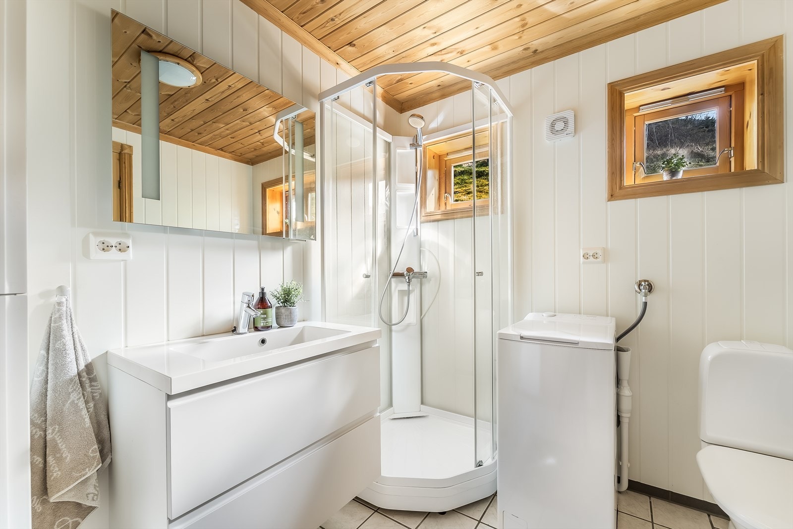 Lyst og moderne bad med stilrent design. Praktisk dusjkabinett og oppbevaringsplass i baderomsinnredning. Galleribilde