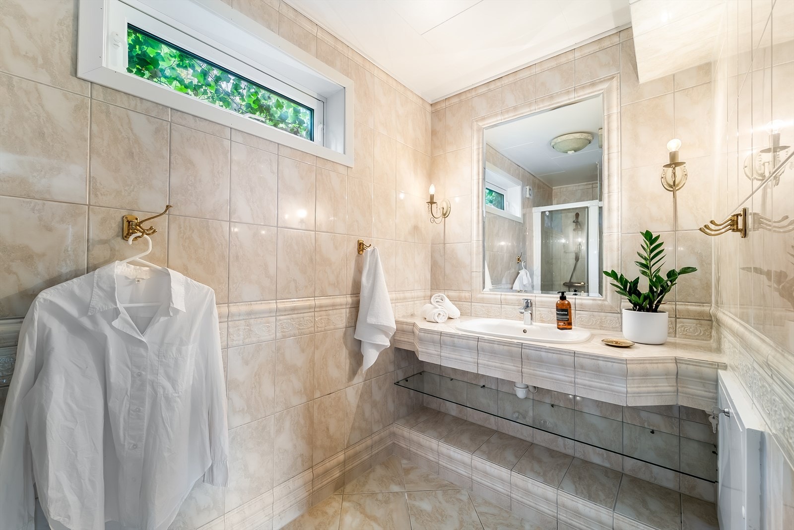 Pent fliselagt bad med tilpasset baderomsinnredning, toalett og dusjløsning. Galleribilde