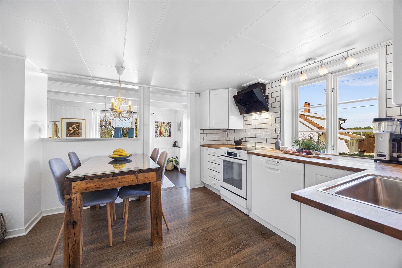 Pent, hvitmalt kjøkken med plass til spisebord. Galleribilde