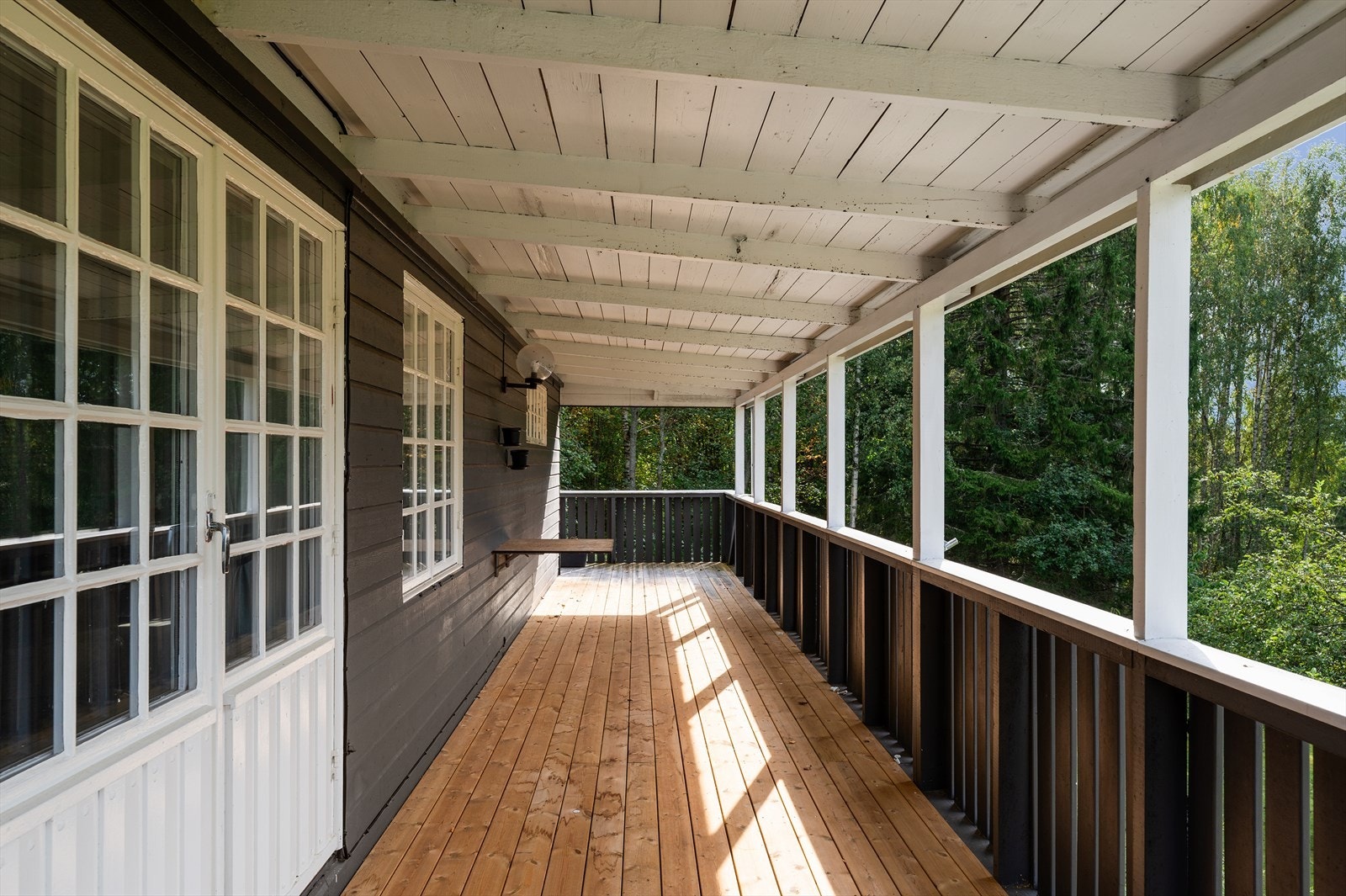 Boligen har en hyggelig platting ved inngangen, en solrik terrasse utenfor det ene soverommet, og en overbygget veranda utenfor stuen i tilbygget del - perfekt for avslapning og sosiale sammenkomster gjennom store deler av året. Galleribilde